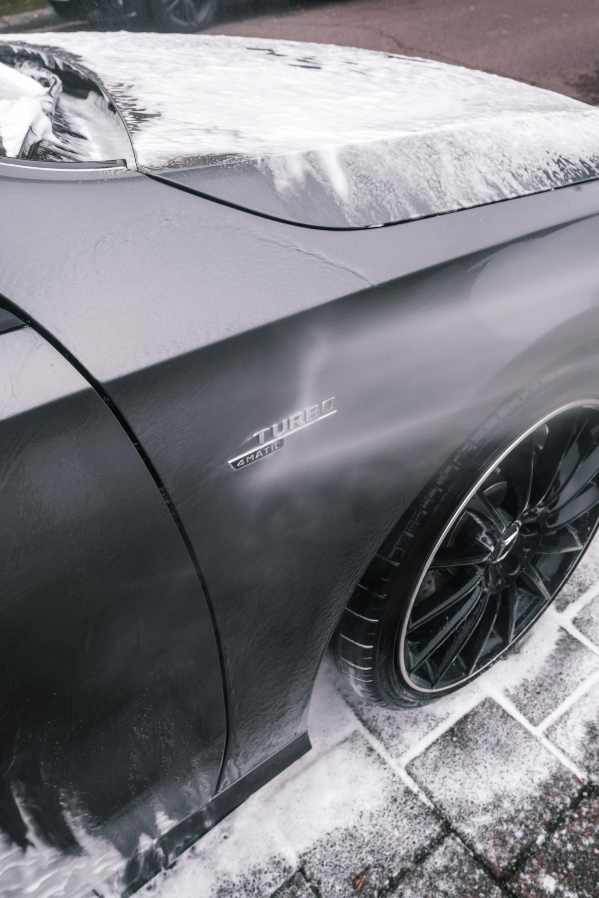 Dark vehicle covered in rich foam during a premium hand wash