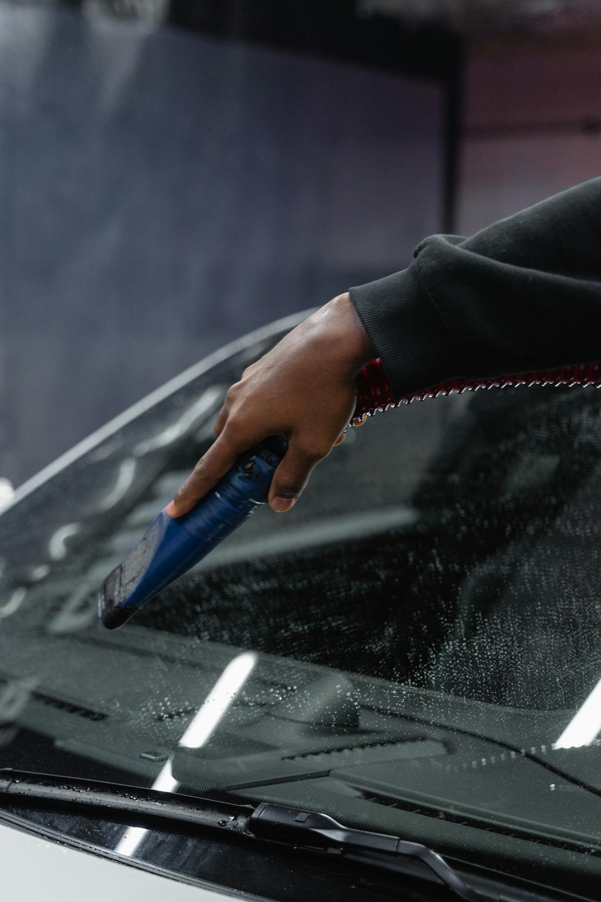 Hand drying a car windshield inside a car wash